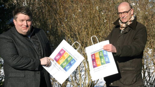 Falk Herzog und Hans-Wilhelm Hagen (WVE) präsentieren die mit Webers Portrait bedruckten Eutiner Einkaufstaschen